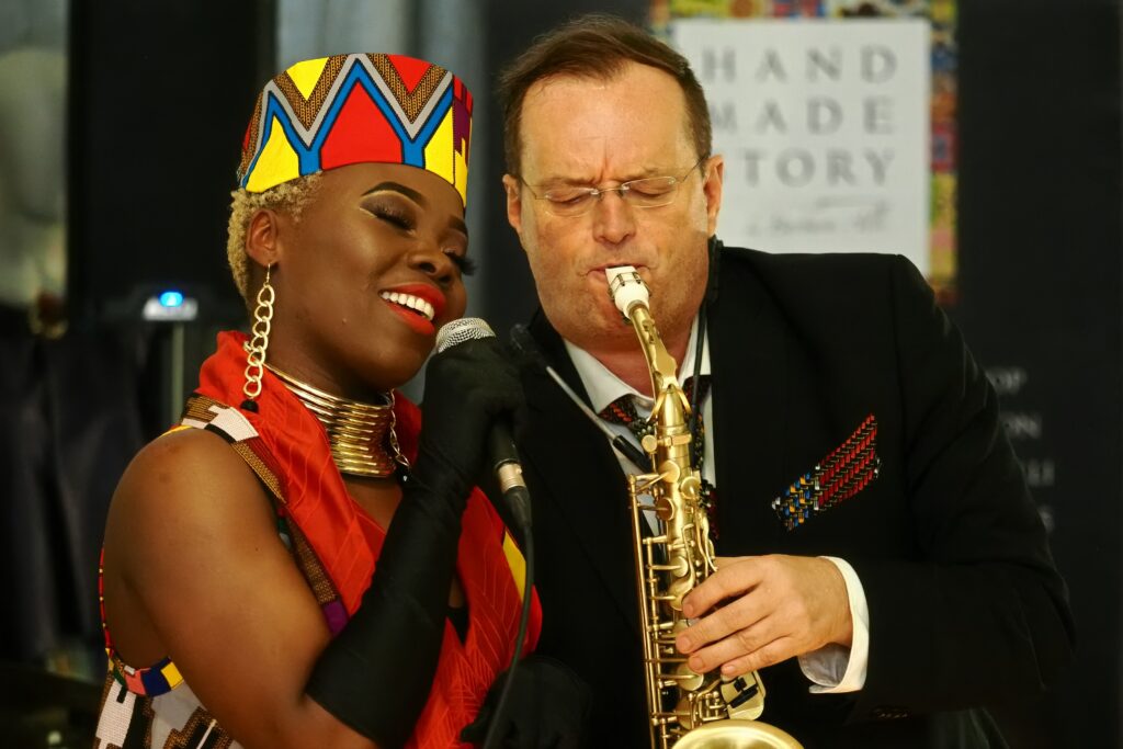 A lady singing beside a man playing a saxophone