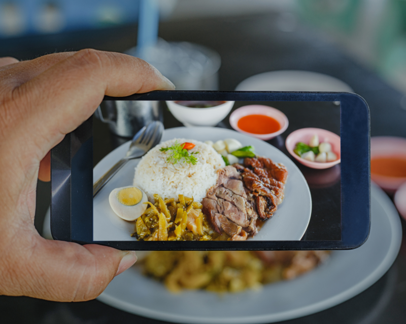 Food Photography: A man using a smartphone to take a picture of rice dished in white ceramic