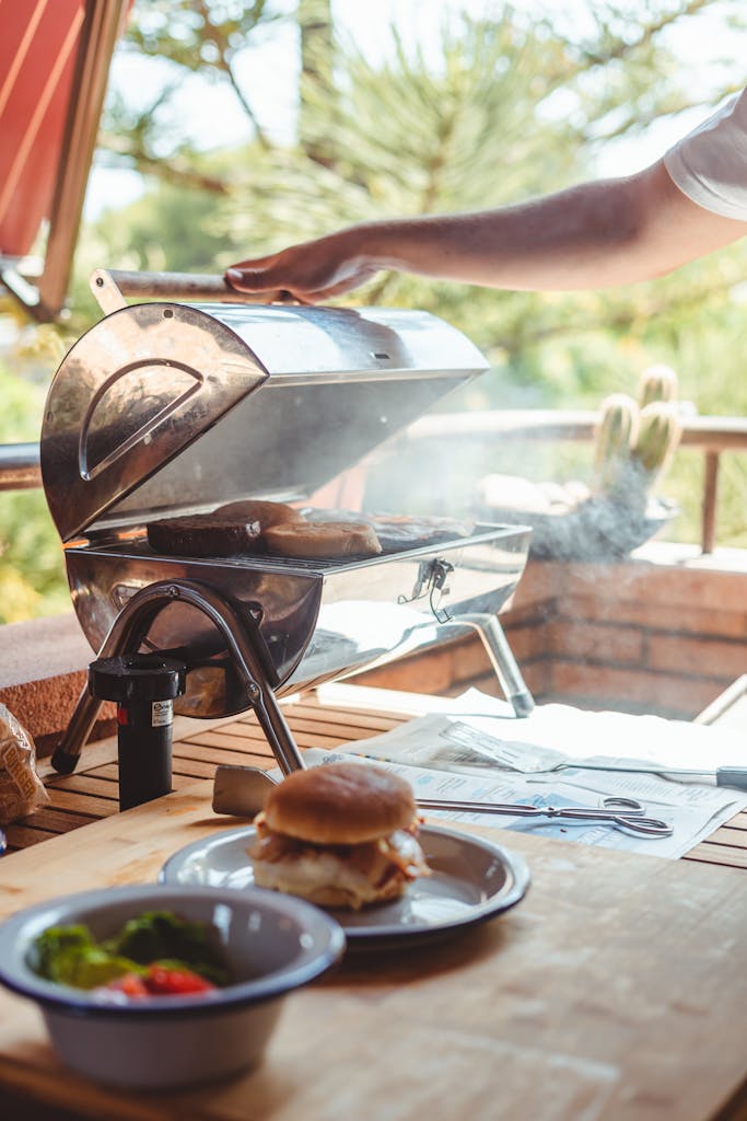 Crop anonymous male opening barbecue grill with fried bread for preparing burgers in nature