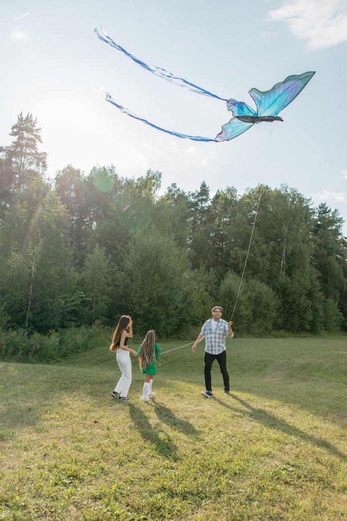 Father Flying a Butterfly Shaped Kite With Two Daughters