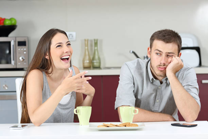 A couple sitting together, with the man looking frustrated while the woman appears distant, highlighting the challenge of transitioning from friendship to romance.