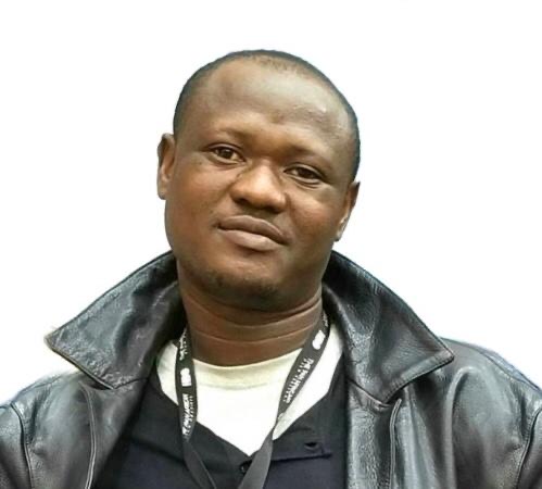 Damola Adepoju standing in front of a white canva