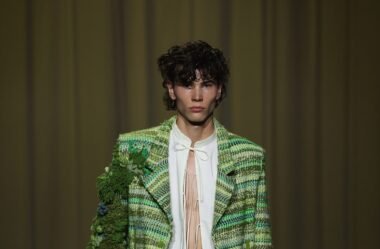 Model in Danny Reinke’s The Hunt SS26 collection wearing a flowing olive silk dress with medieval-inspired lace-up details, symbolizing transformation and inner freedom.