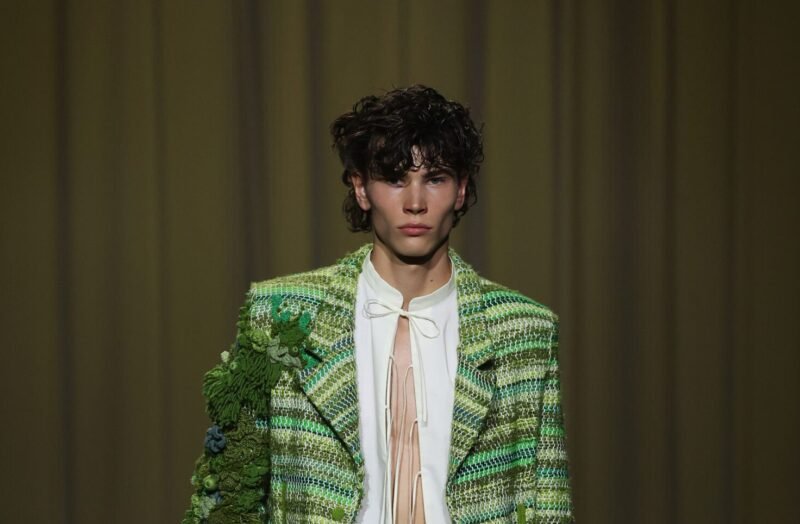Model in Danny Reinke’s The Hunt SS26 collection wearing a flowing olive silk dress with medieval-inspired lace-up details, symbolizing transformation and inner freedom.