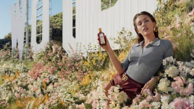 Gucci Flora Gorgeous Gardenia Intense perfume bottle glowing in sunlight with floral design and fuchsia glass.