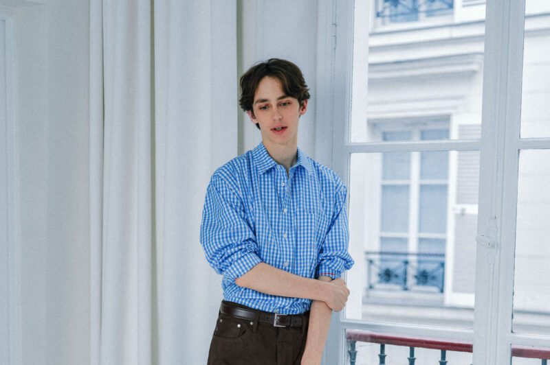 Model wearing sunflower-printed VOWELS SS26 denim chore jacket at Paris Fashion Week